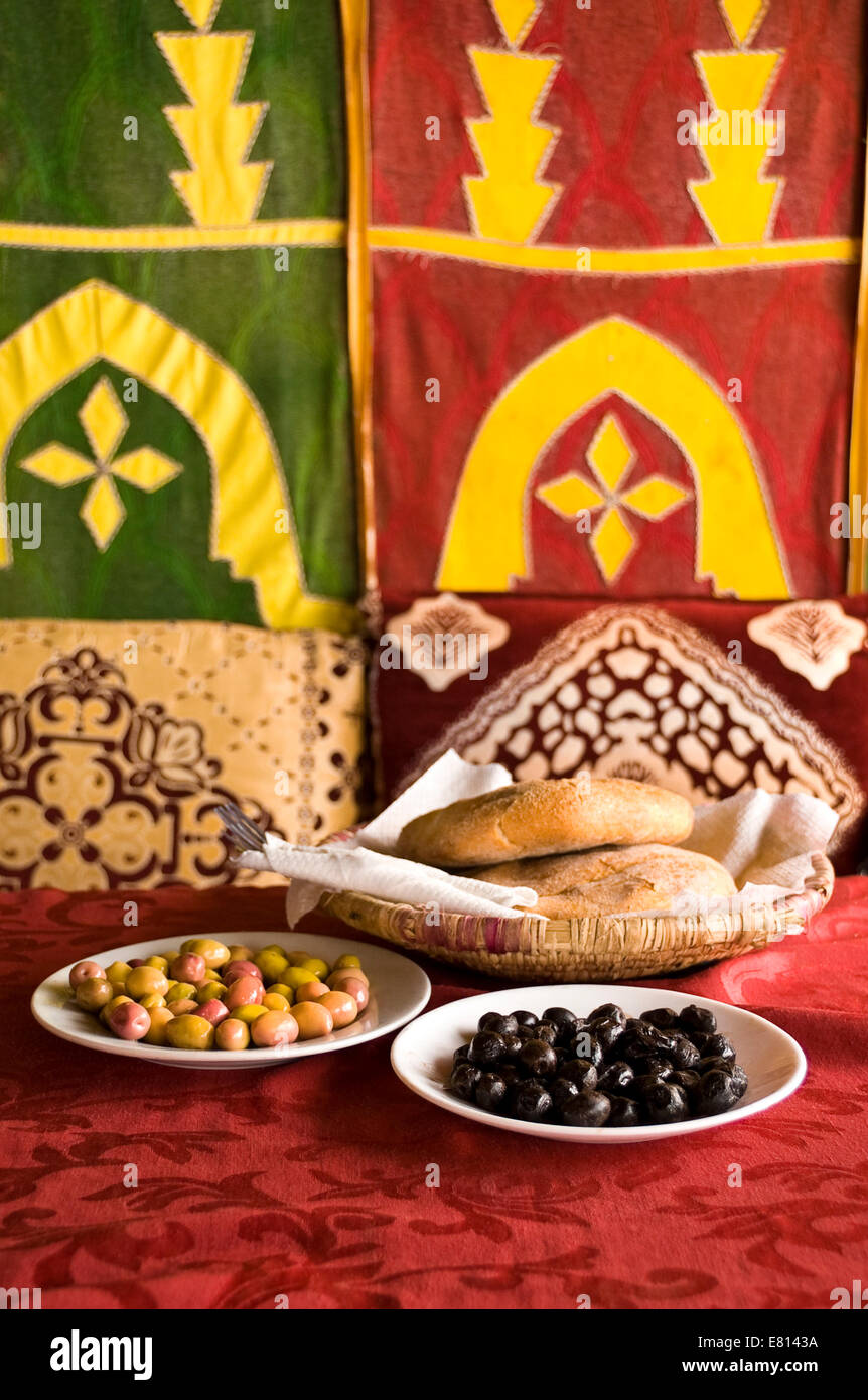 Vertical close up of traditional Moroccan bread, khobz, served with green and black olives in Marrakech. Stock Photo