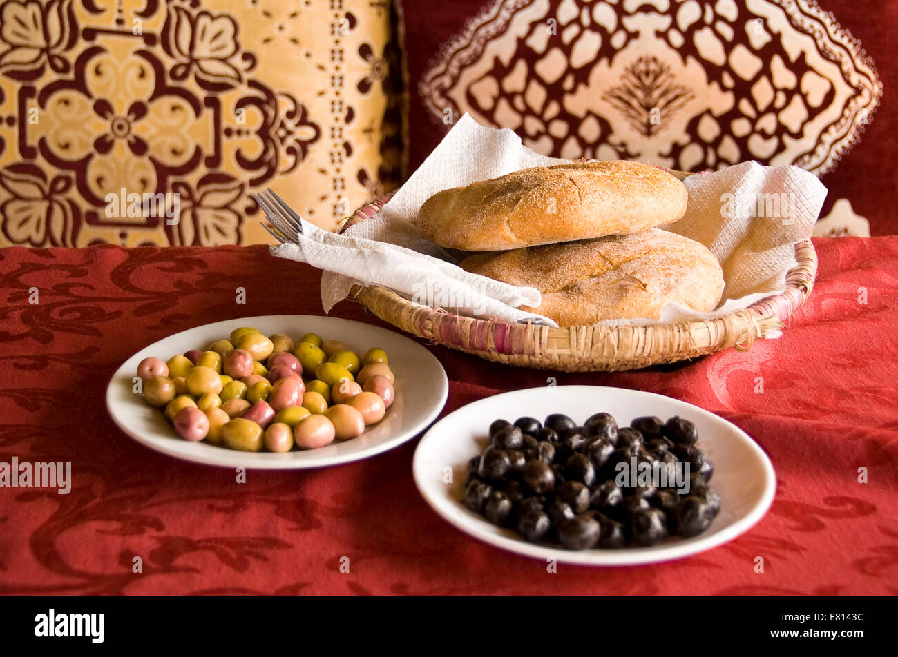 Horizontal close up of traditional Moroccan bread, khobz, served with green and black olives in Marrakech. Stock Photo
