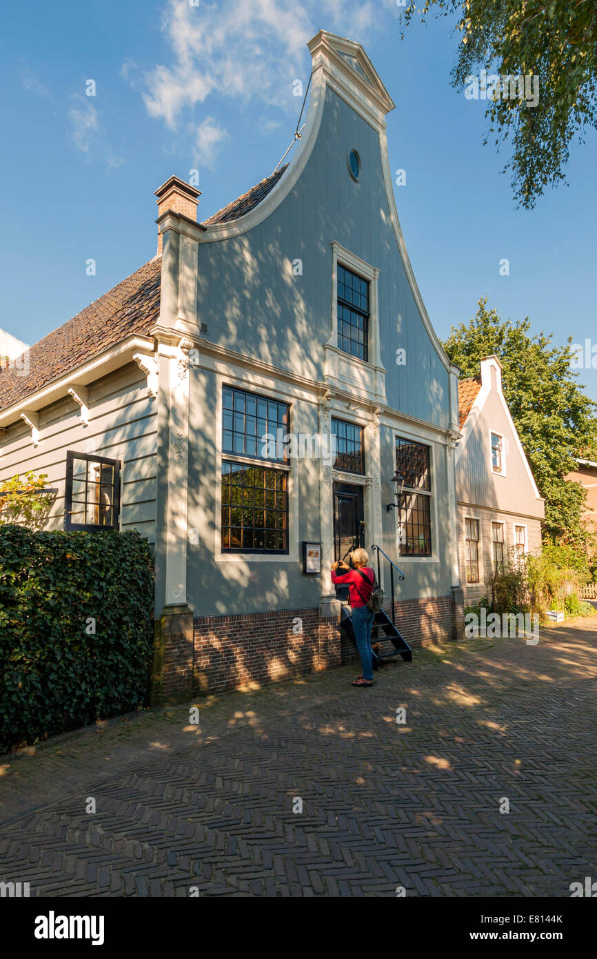 Woman taking a photo of a historic house in 'Broek in Waterland', North Holland, The Netherlands. Stock Photo