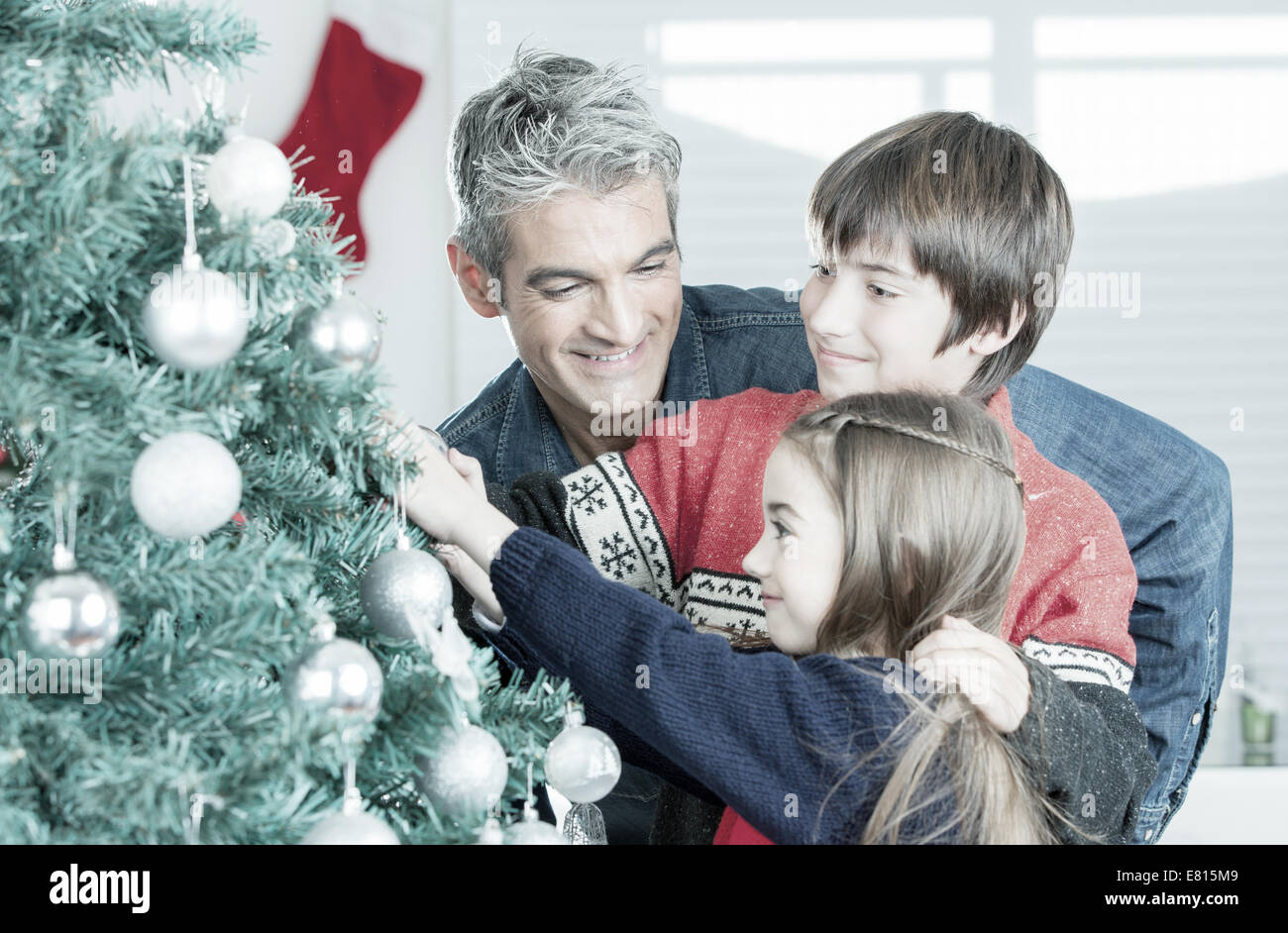 Father with son and daughter decorating Christmas tree. Family Christmas concept. Stock Photo