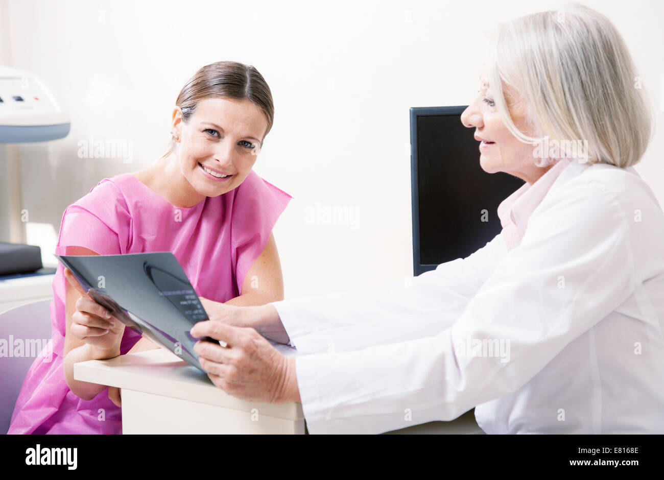Happy doctor and female patient looking at medical scan results. Stock Photo