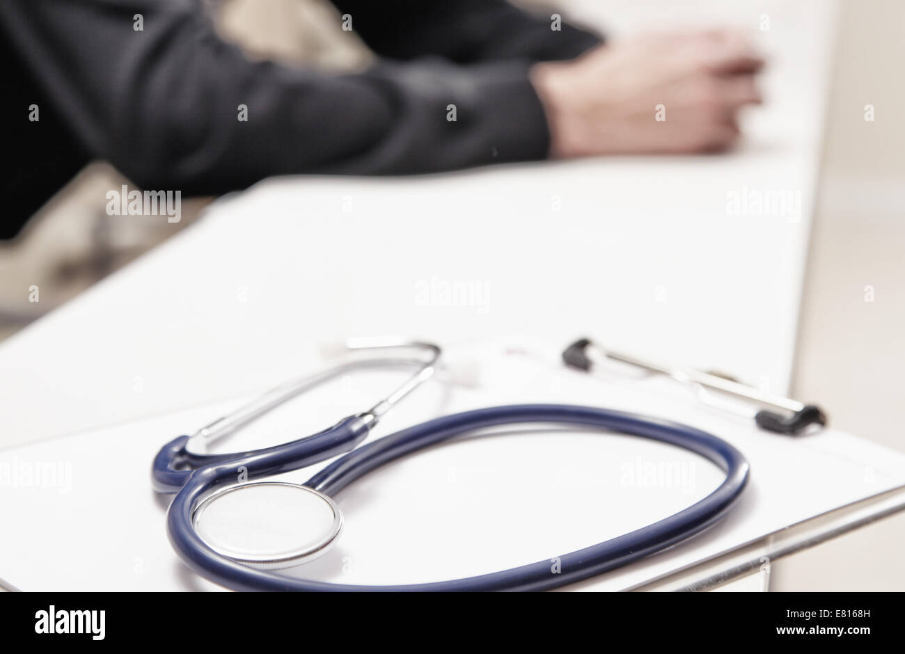 Stethoscope on the desk with doctor in background. Stock Photo