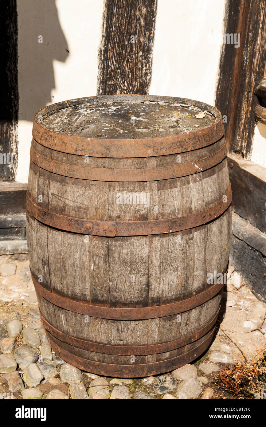Large traditional oak barrel standing alone in an ancient cobble stone courtyard. Stock Photo