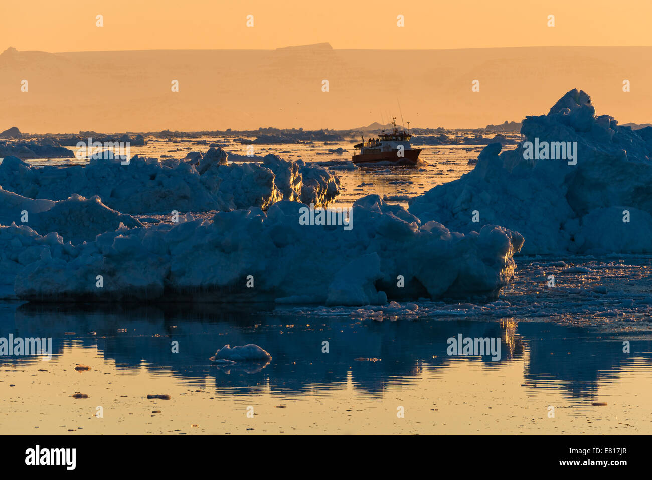 Boat and glaciers in the ocean at sunset. Ilulissat, Greenland Stock Photo