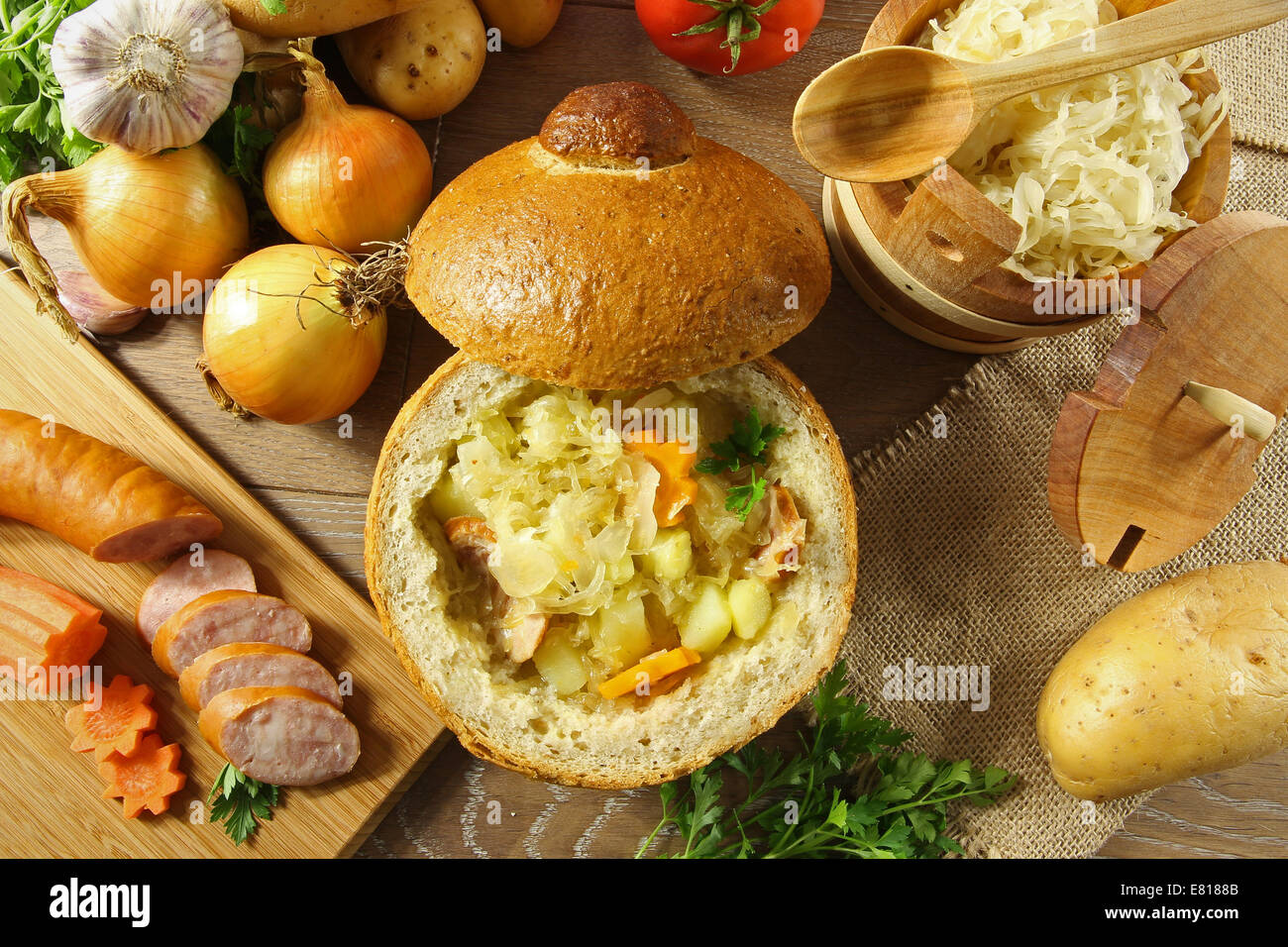 Cabbage soup in a loaf of bread and vegetables on a wooden table Stock Photo