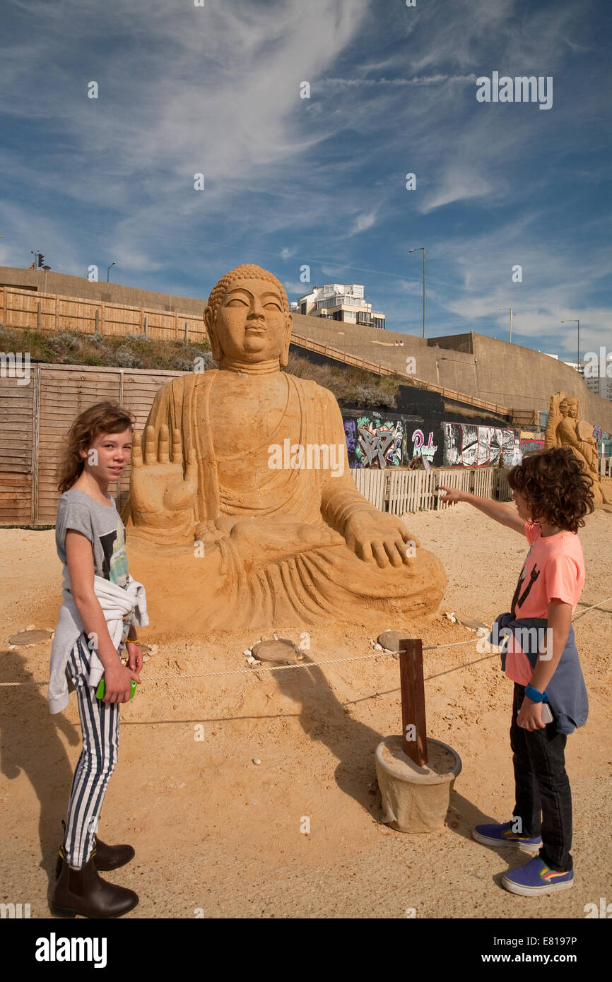 Two children admire the Tian Tan Buddha on display at the Sand Sculpture festival in Brighton Stock Photo