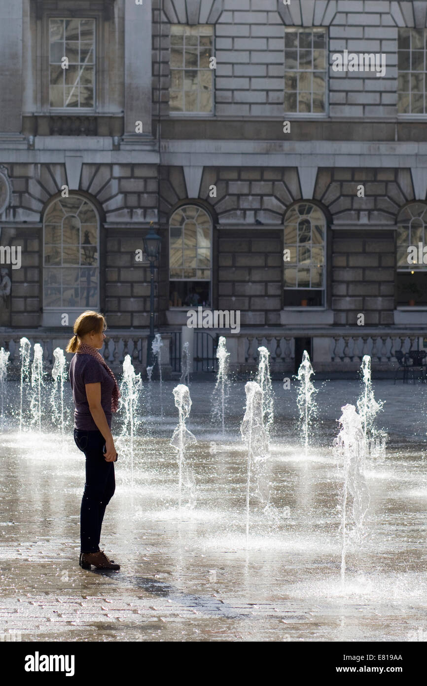 Lady having her picture taken within the water display at Somerset House courtyard London England Stock Photo