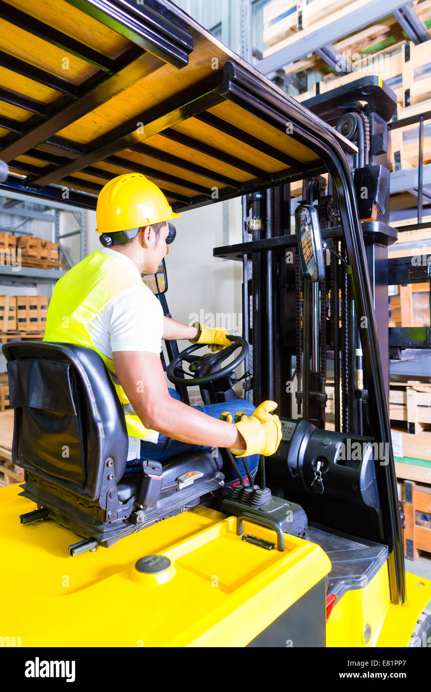 Asian fork lift truck driver lifting pallet in storage warehouse Stock Photo Alamy