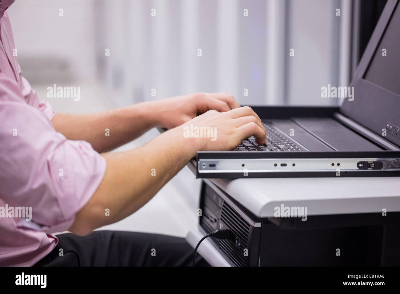 Close up of technician sitting using laptop to diagnose servers Stock Photo