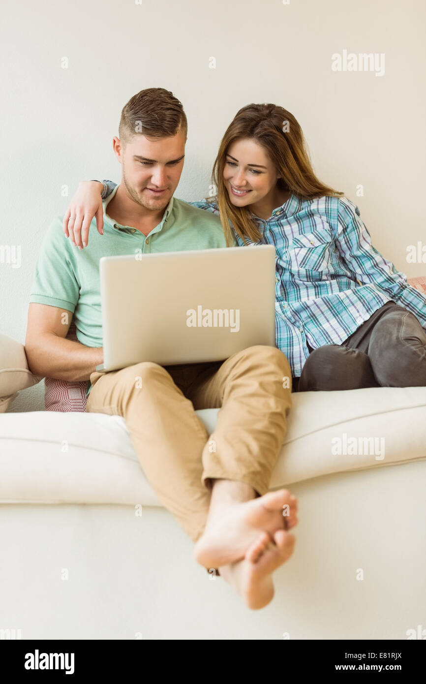 Cute couple relaxing on couch with laptop Stock Photo - Alamy