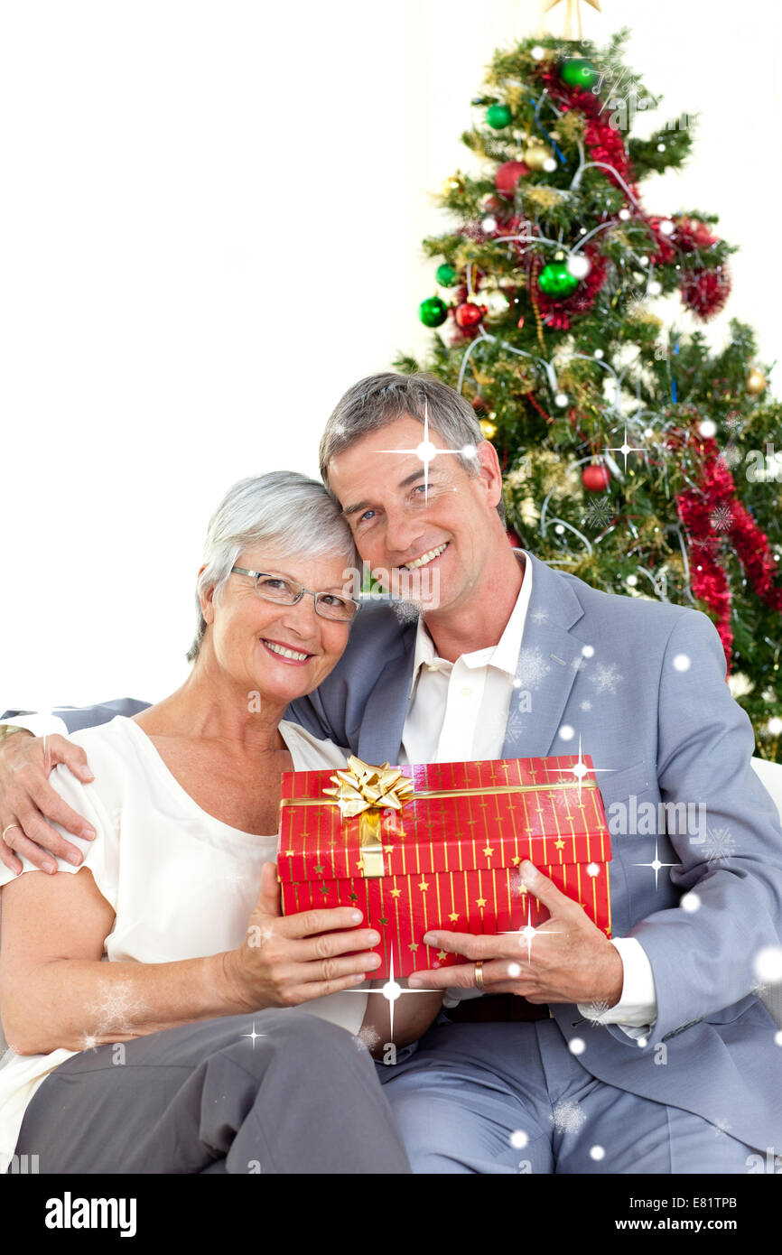 Composite image of senior couple holding a christmas present Stock Photo