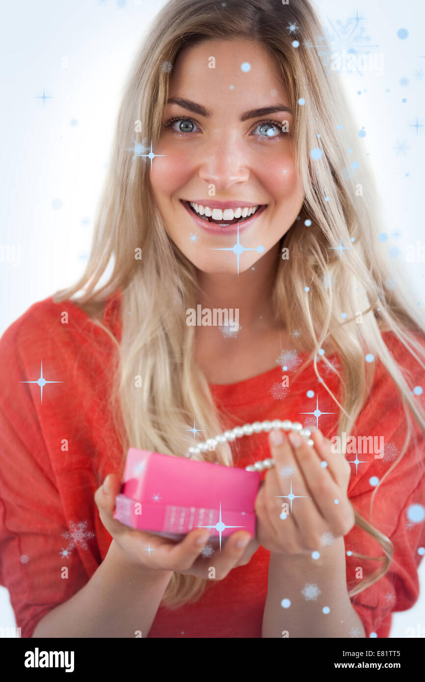 Composite image of cheerful woman discovering necklace in a gift box Stock Photo