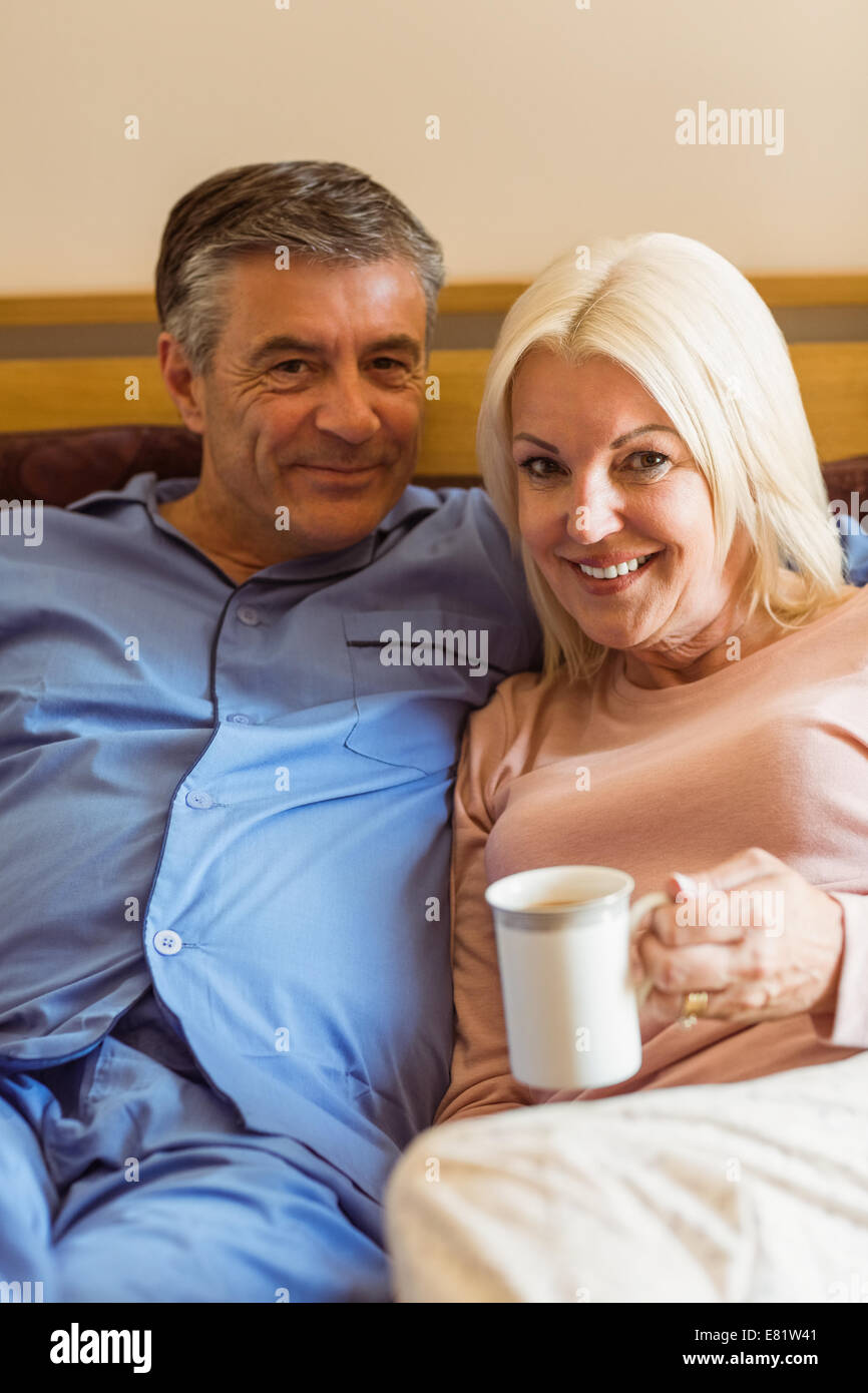 Happy mature couple smiling at camera on bed Stock Photo