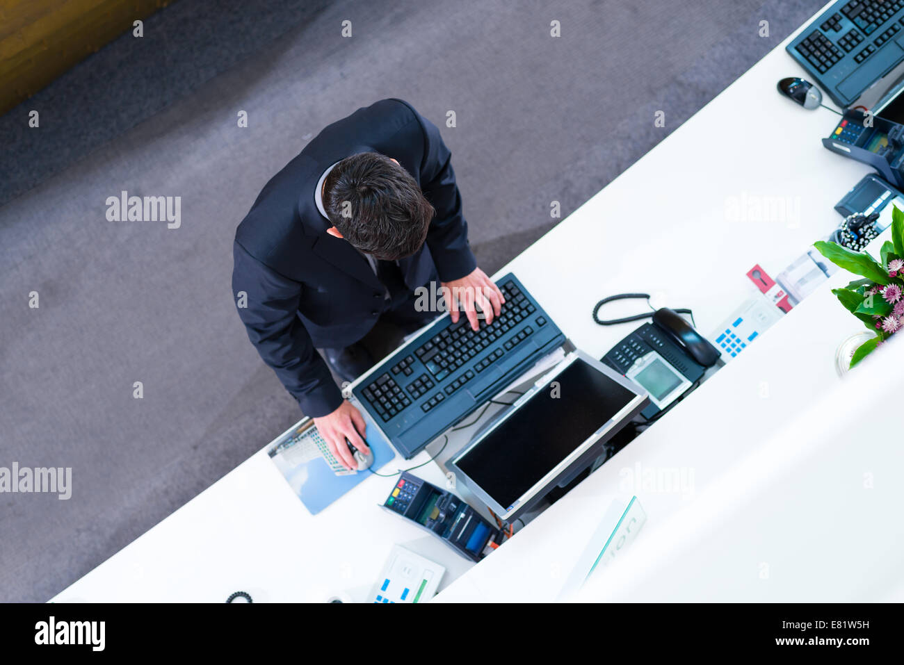 Hotel receptionist working on computer at front desk office Stock Photo
