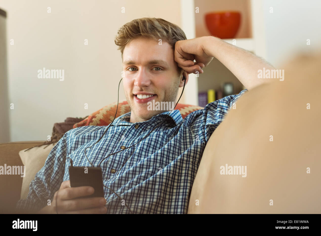Young man listening to music on his couch Stock Photo Alamy