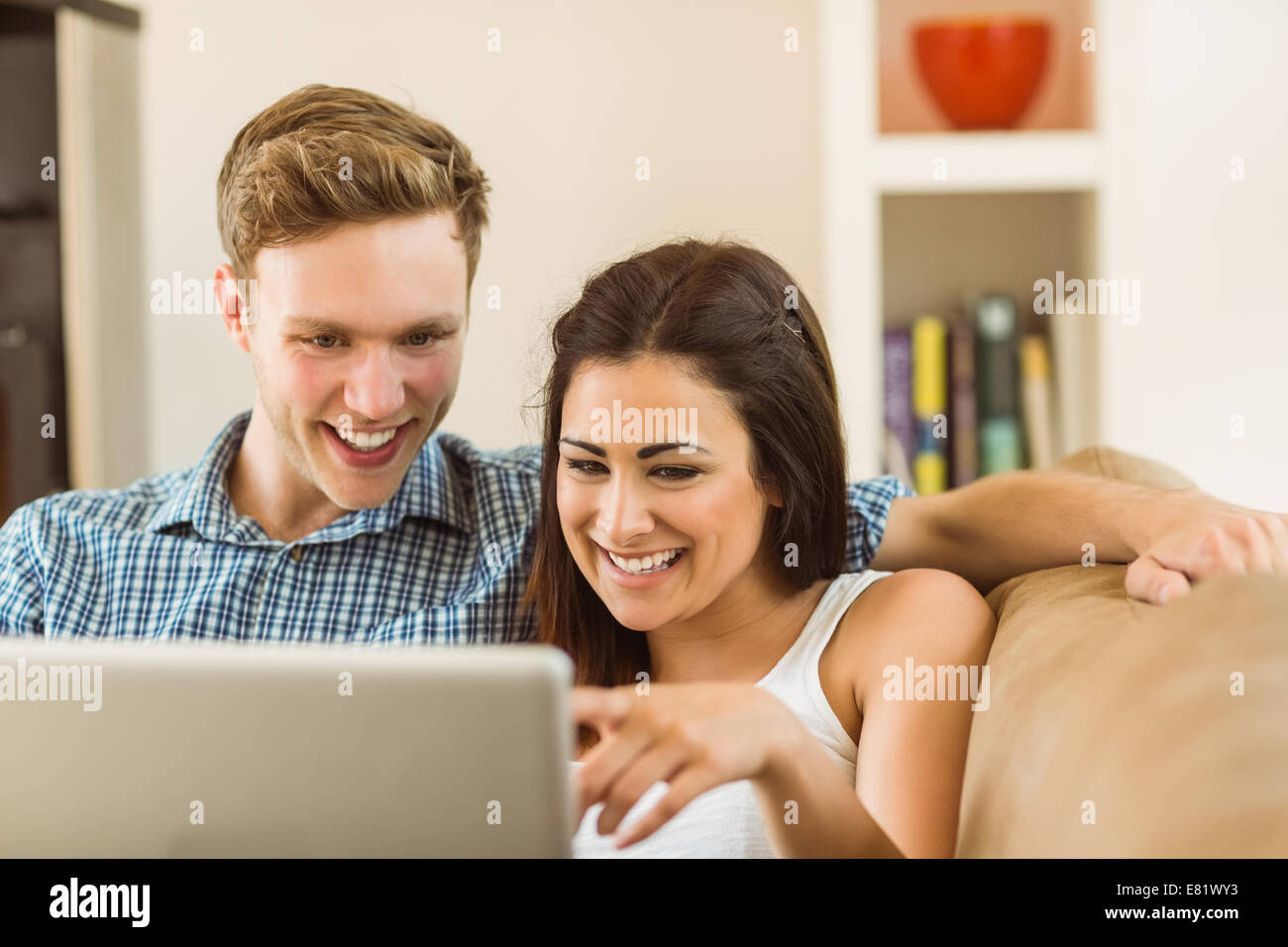 Happy young couple relaxing on the couch with laptop Stock Photo - Alamy
