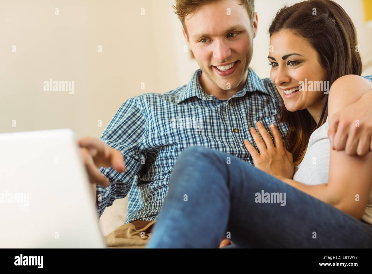 Happy young couple relaxing on the couch with laptop Stock Photo - Alamy