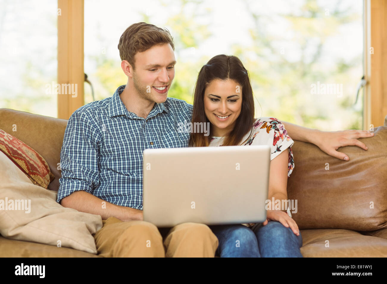 Young cute couple relaxing on couch with laptop Stock Photo - Alamy