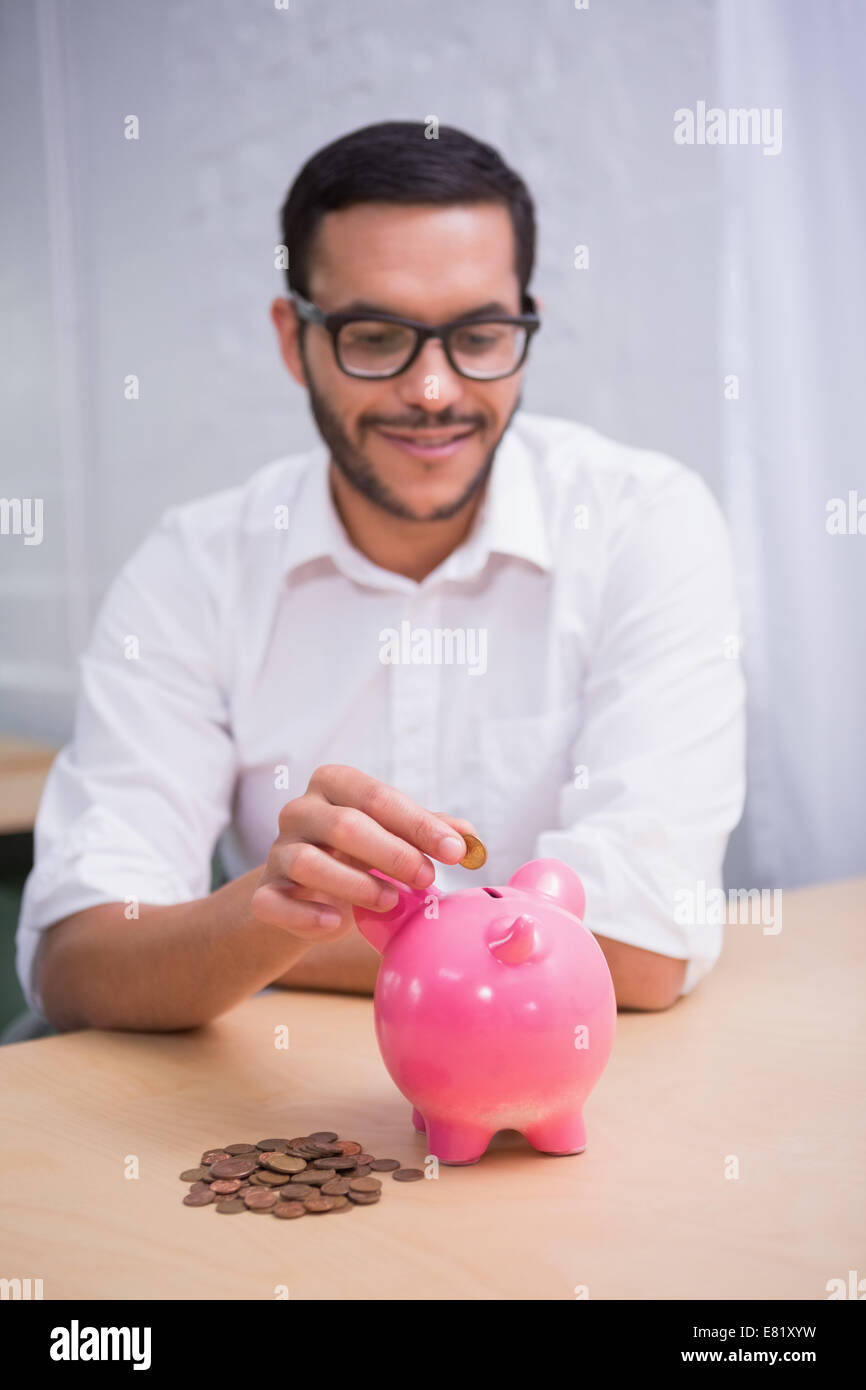 Man putting some coins into piggybank Stock Photo - Alamy
