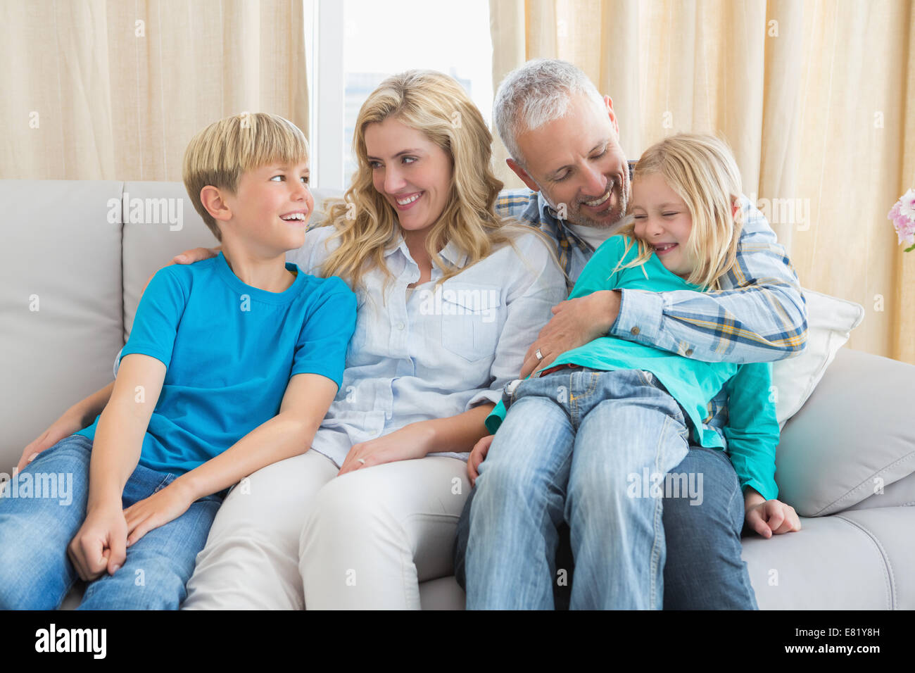Happy family sitting on couch together Stock Photo - Alamy