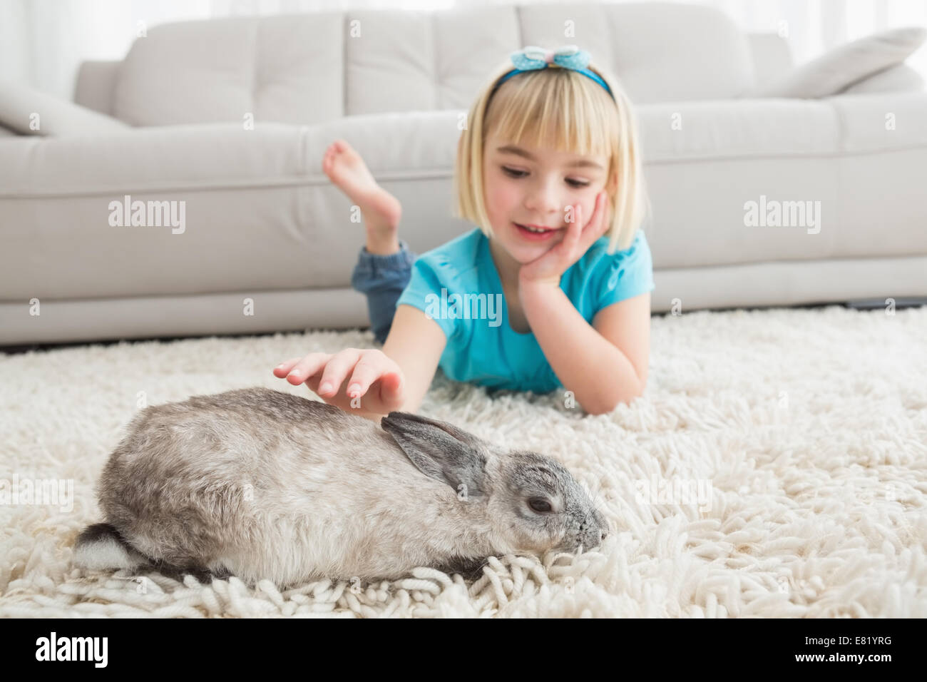 Little girl lying on rug stroking the rabbit Stock Photo Alamy