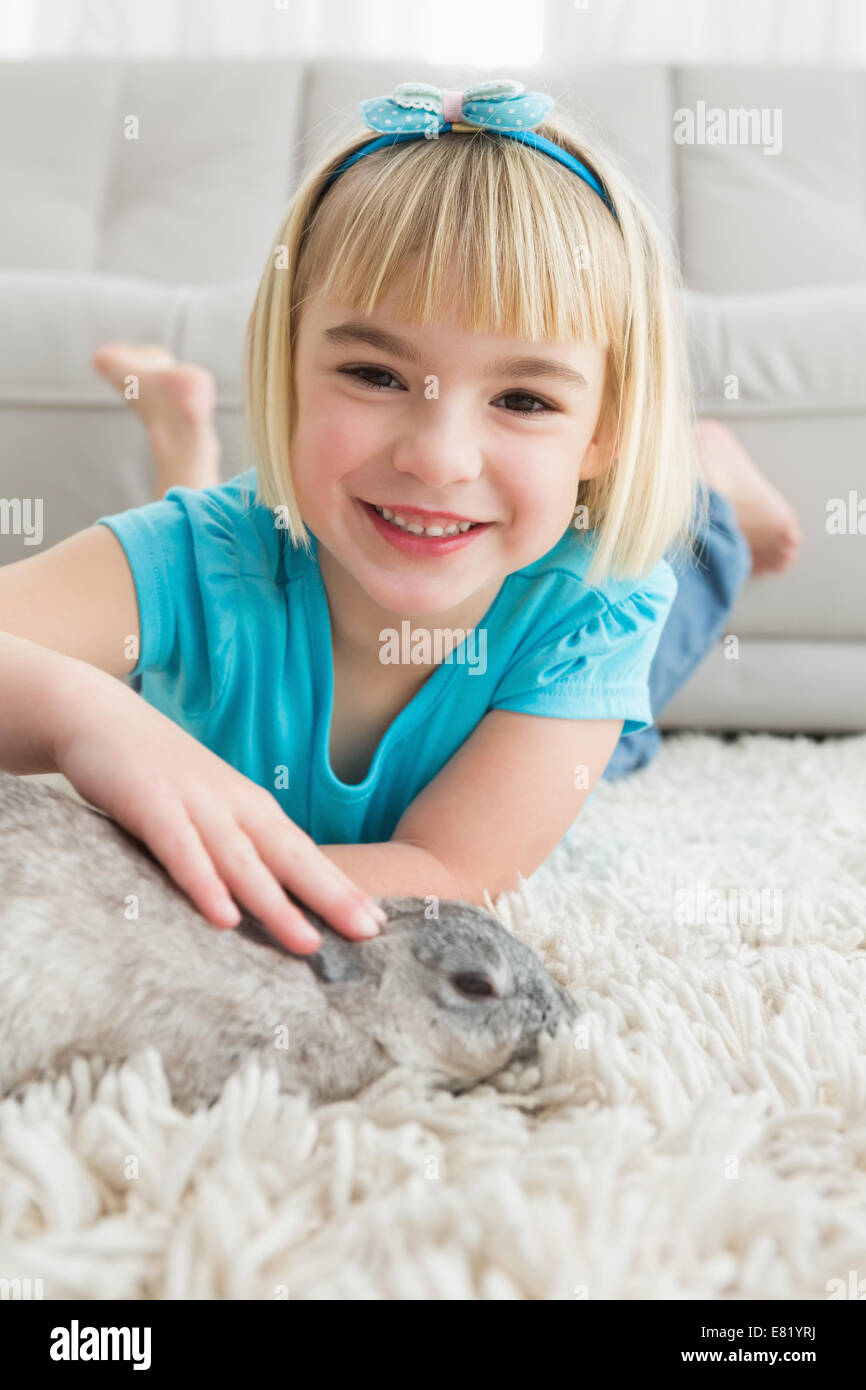 Little girl lying on rug stroking the rabbit Stock Photo Alamy