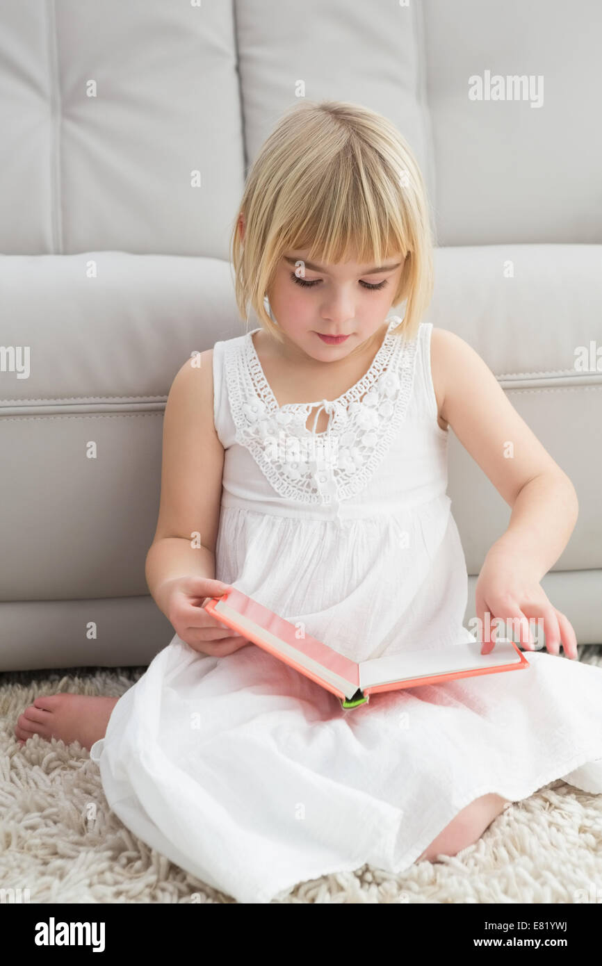 Little girl sitting on the floor reading storybook Stock Photo - Alamy