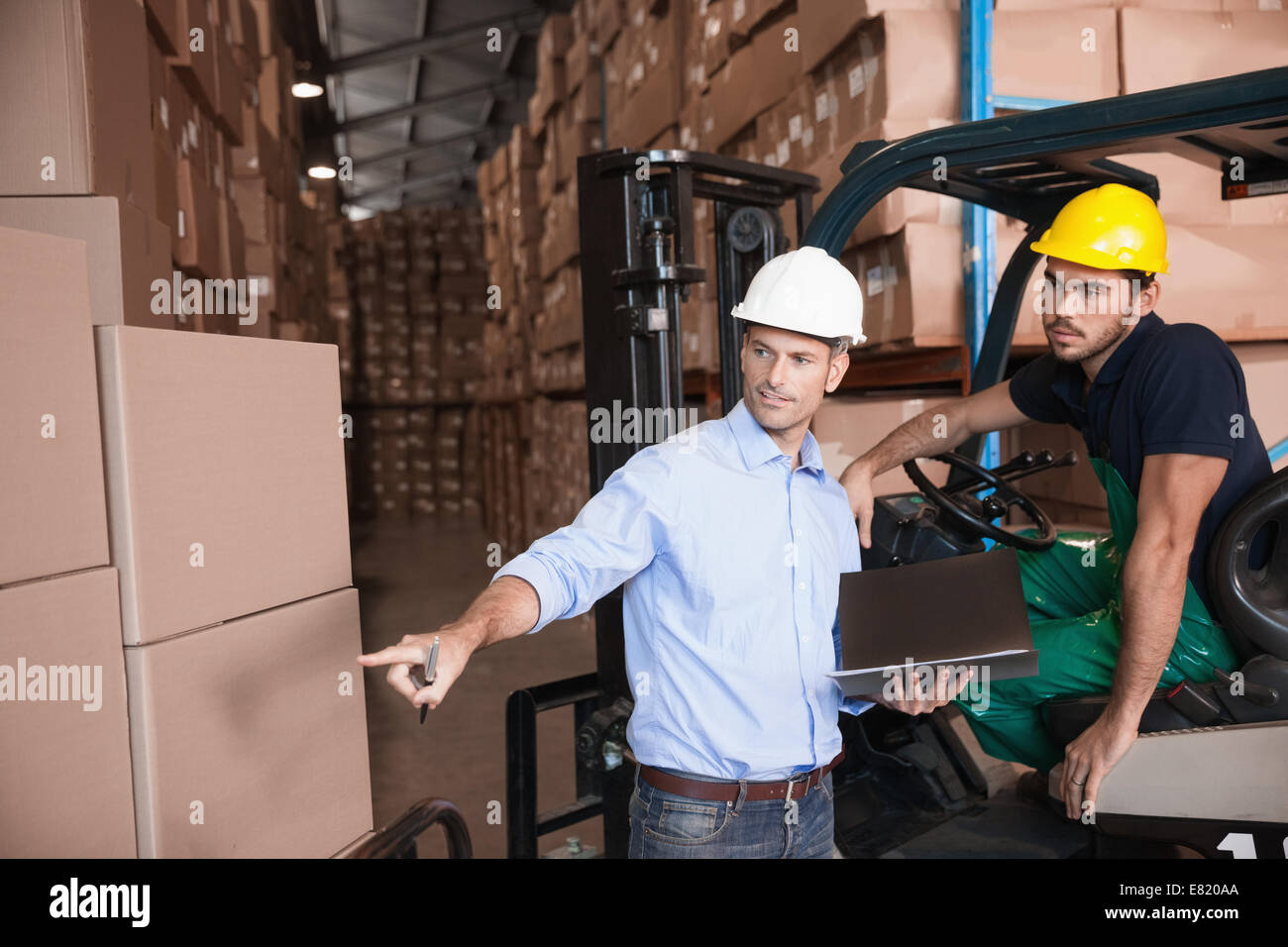 Warehouse manager talking with forklift driver Stock Photo