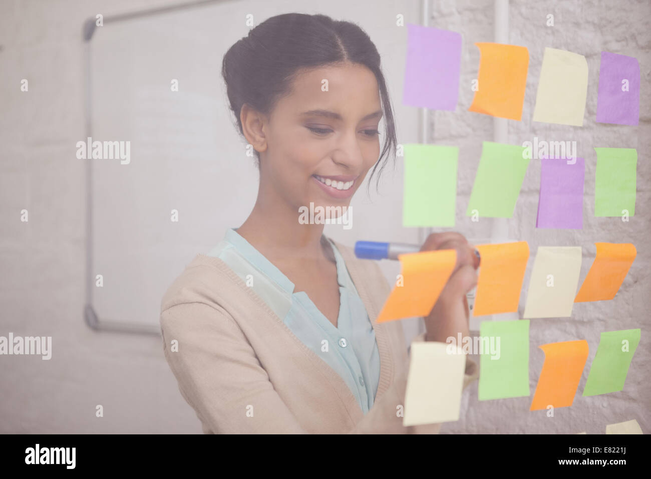 Smiling businesswoman writing on sticky notes on window Stock Photo - Alamy