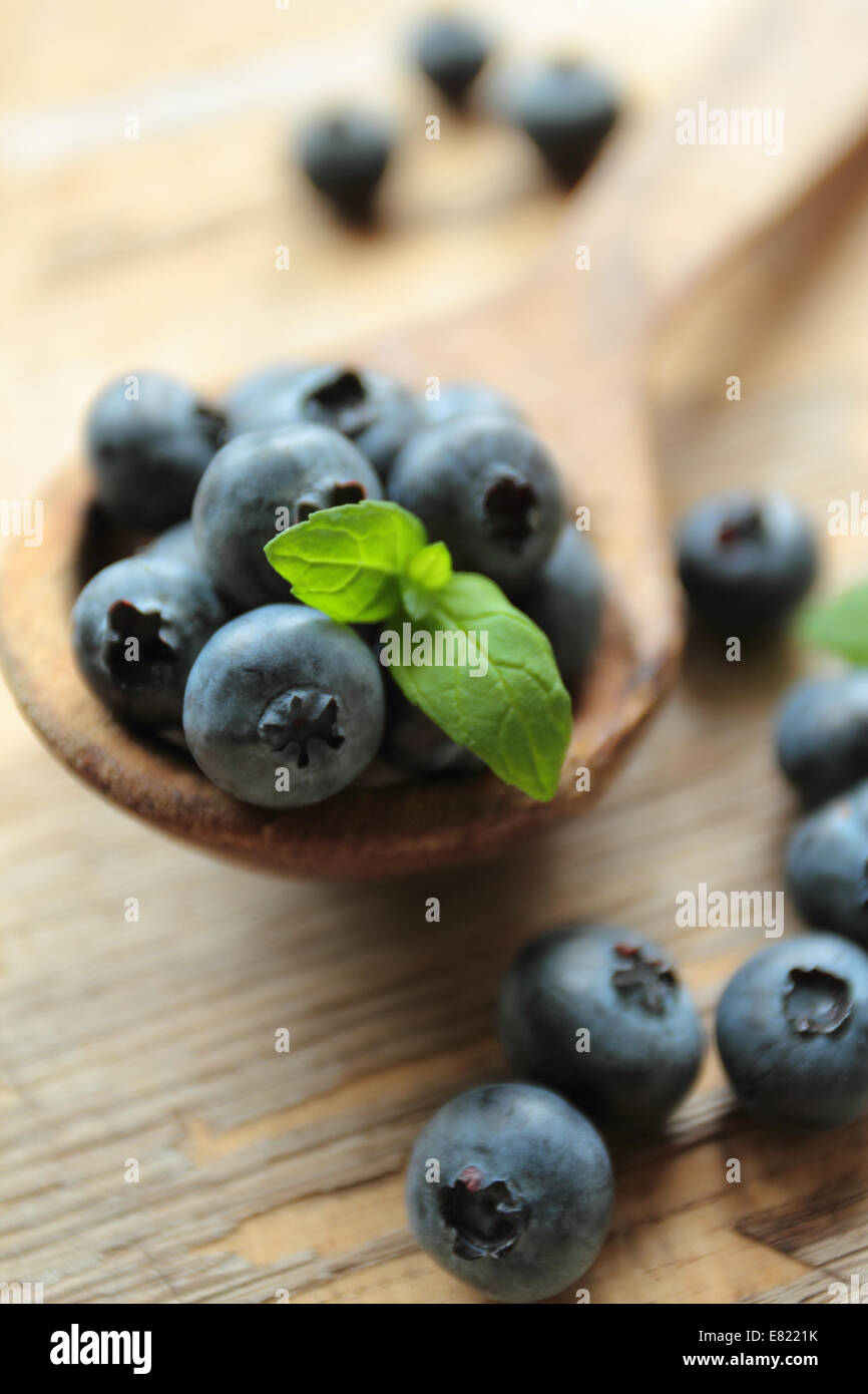 Fresh blueberries fruits with mint leaf on a wooden spoon Stock Photo