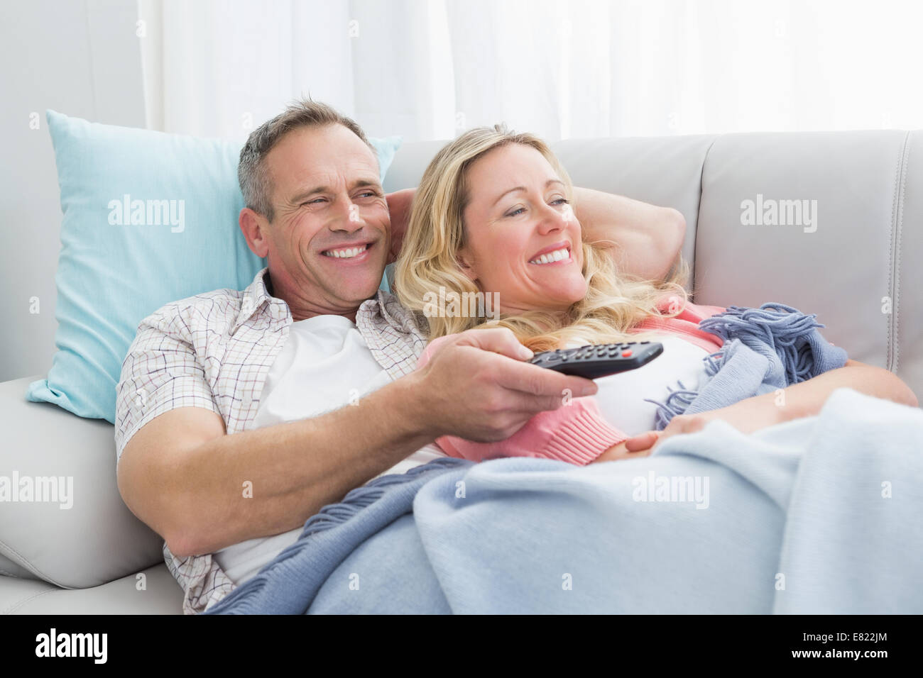 Happy couple cuddling on the couch watching television Stock Photo Alamy