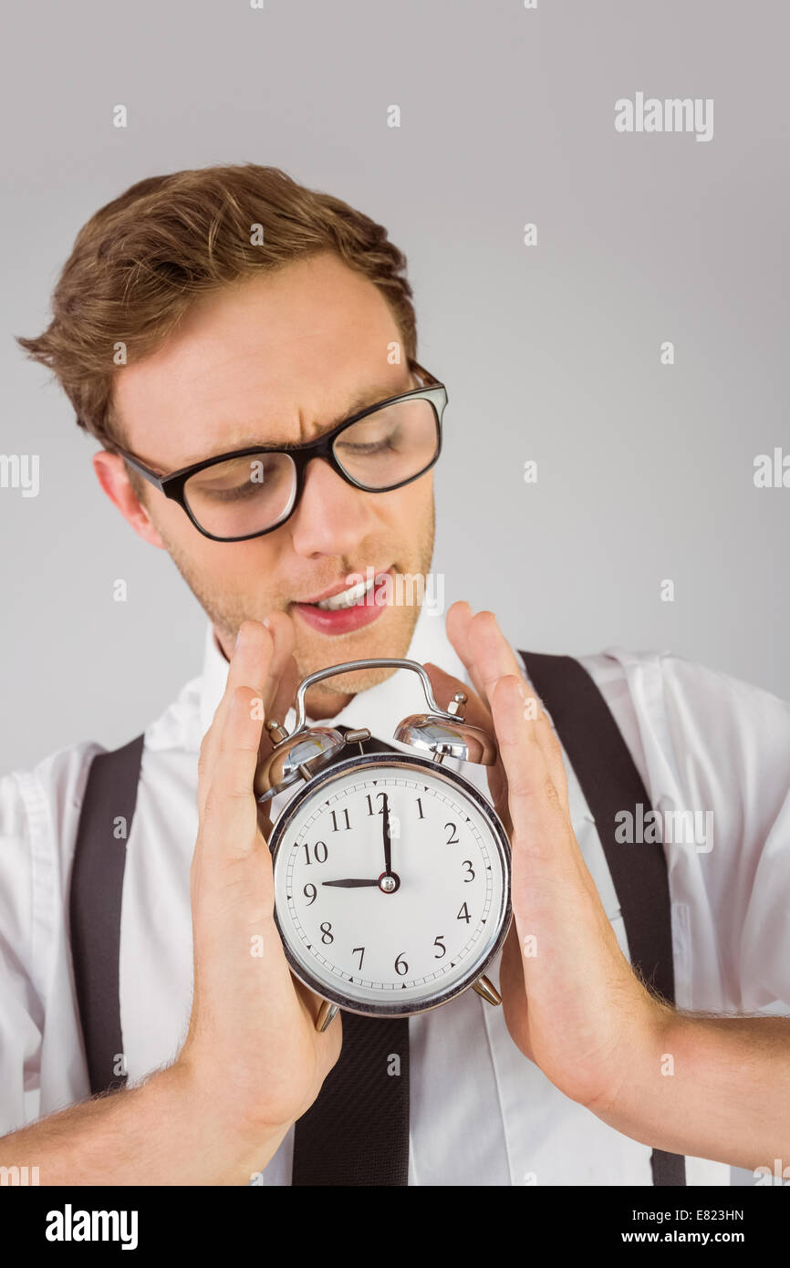 Geeky businessman holding alarm clock Stock Photo