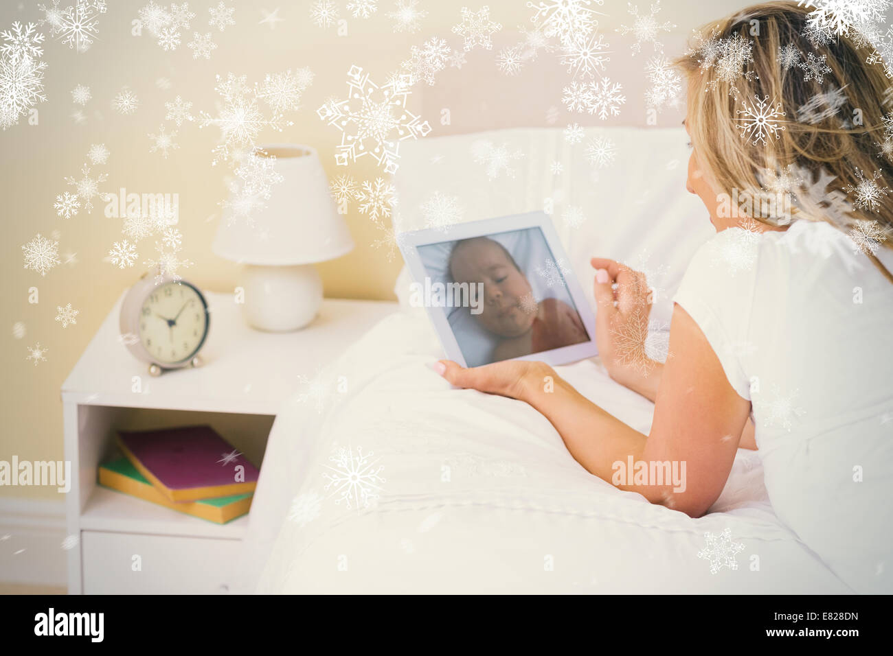 Thoughtful woman using a tablet pc lying on her bed Stock Photo