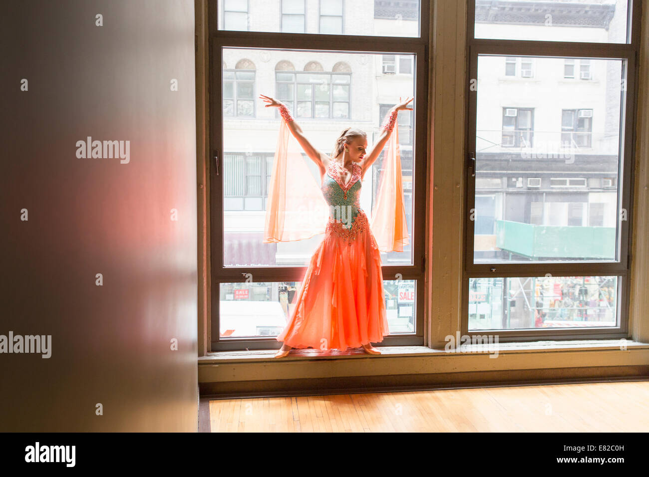 Dancer in dance studio. A woman posing at a window. Stock Photo