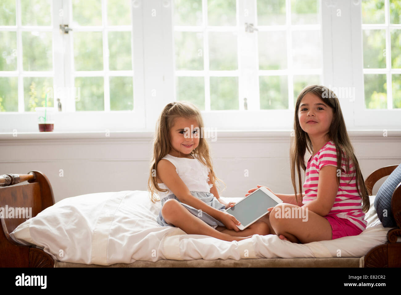 Two girls sitting holding a digital tablet Stock Photo - Alamy