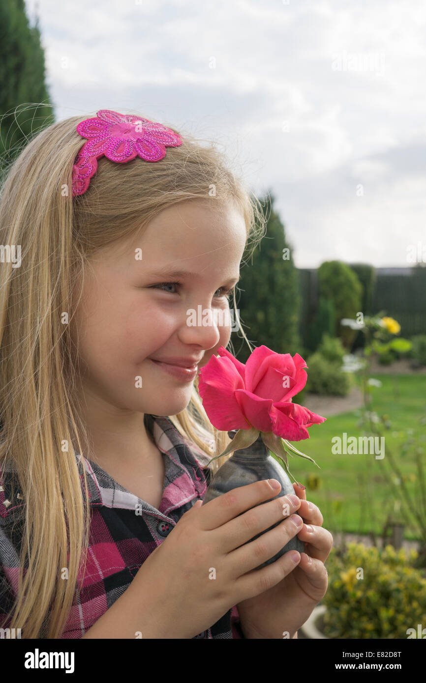 Young girl smelling a red rose. Stock Photo
