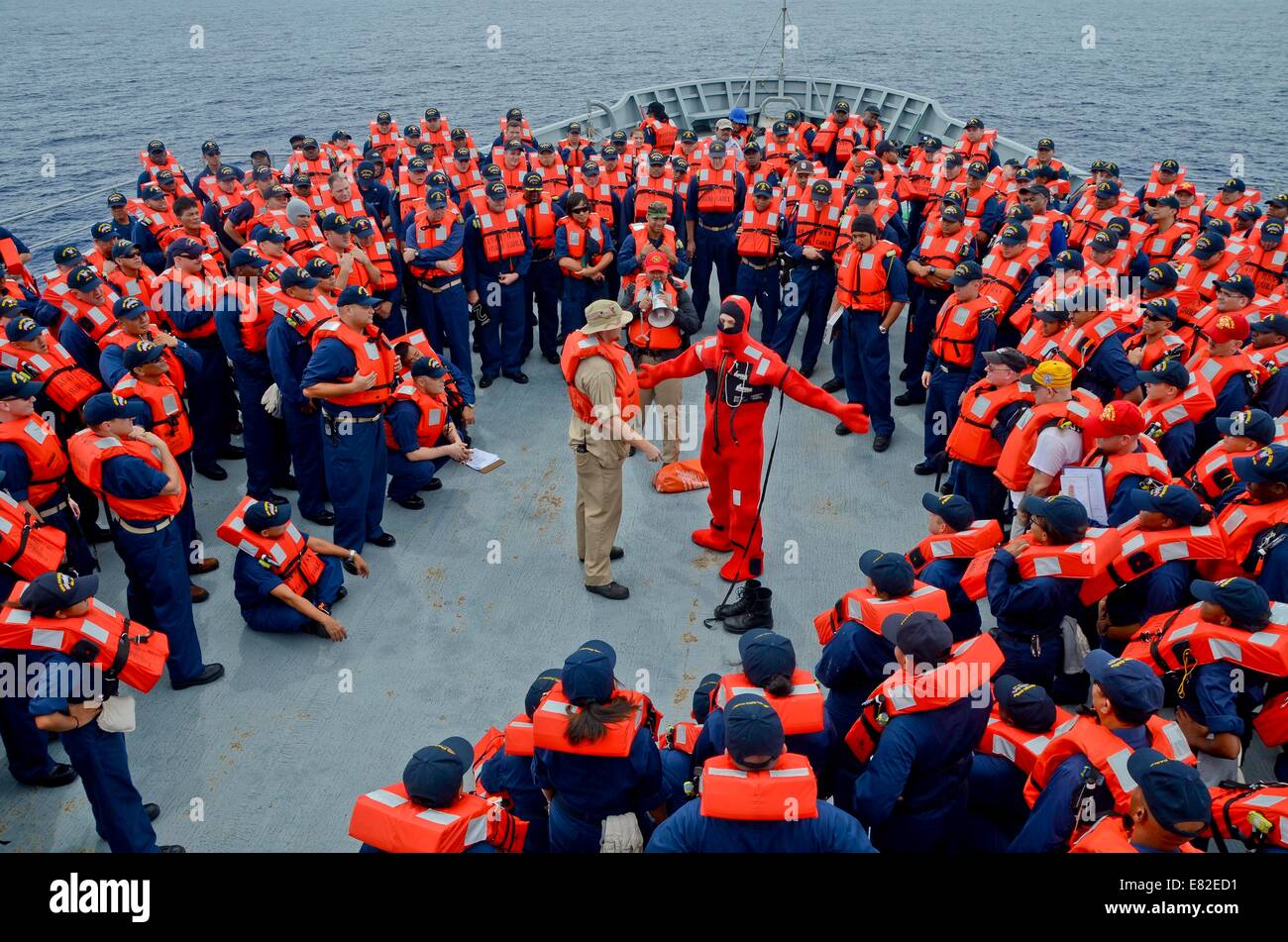 A US Navy Sailor demonstrates an immersion suit to the crew during an