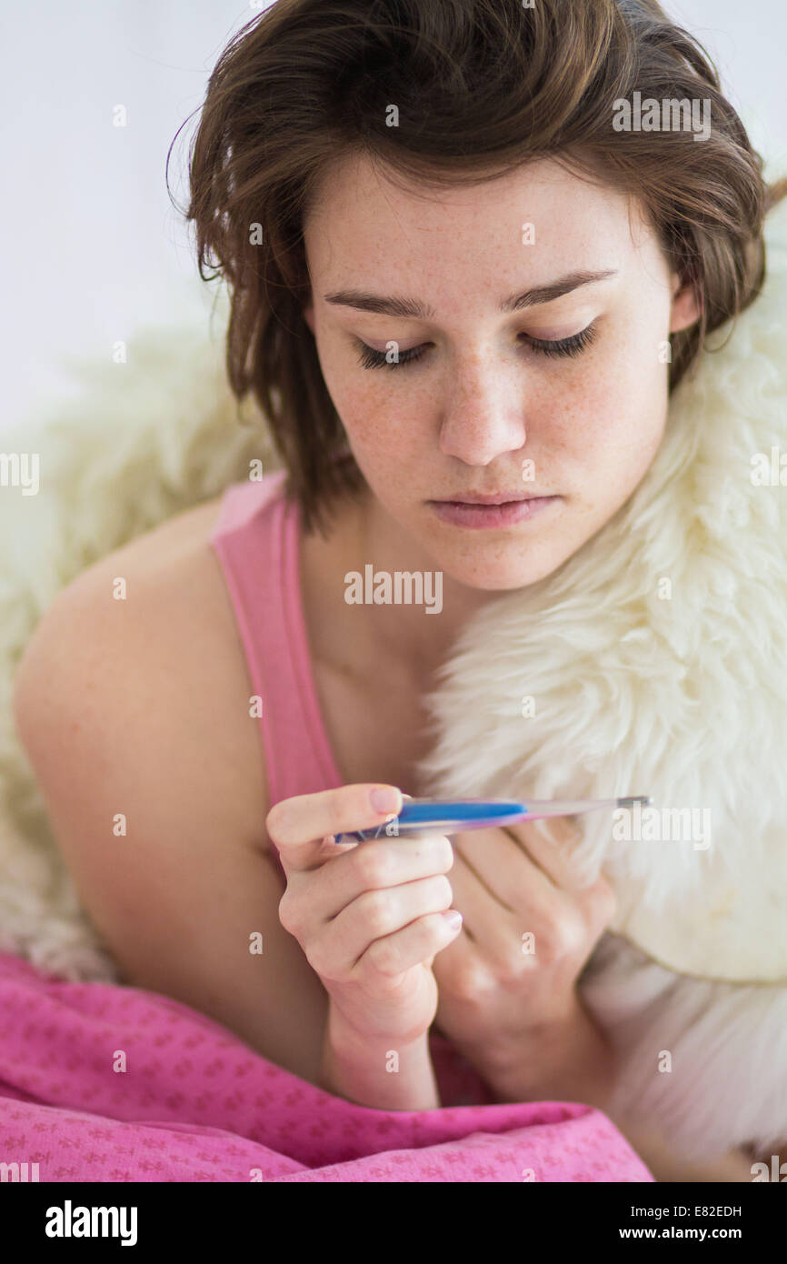 Woman checking her temperature with a digital thermometer Stock Photo