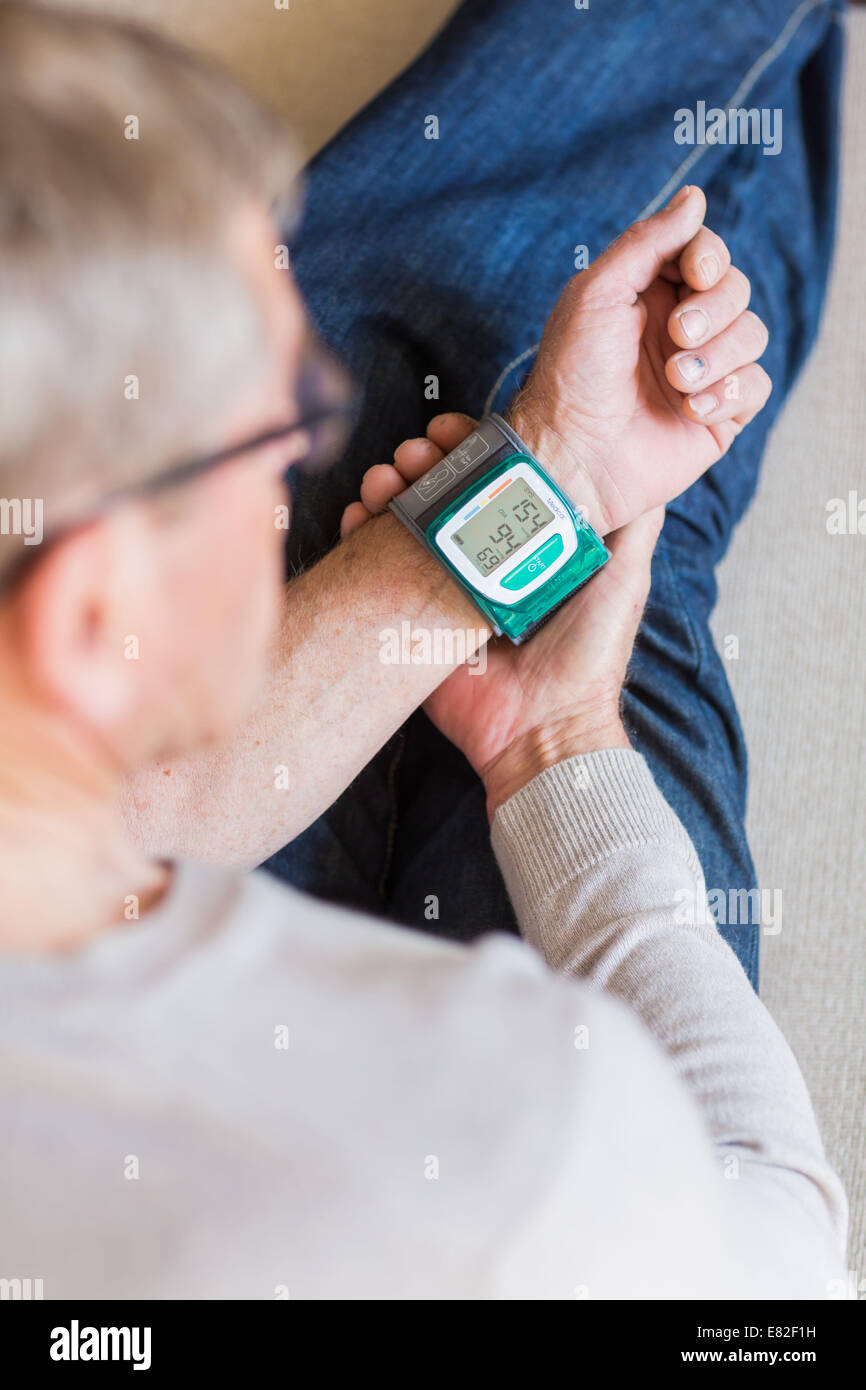 Man taking her blood pressure with a portable blood pressure monitor. Stock Photo