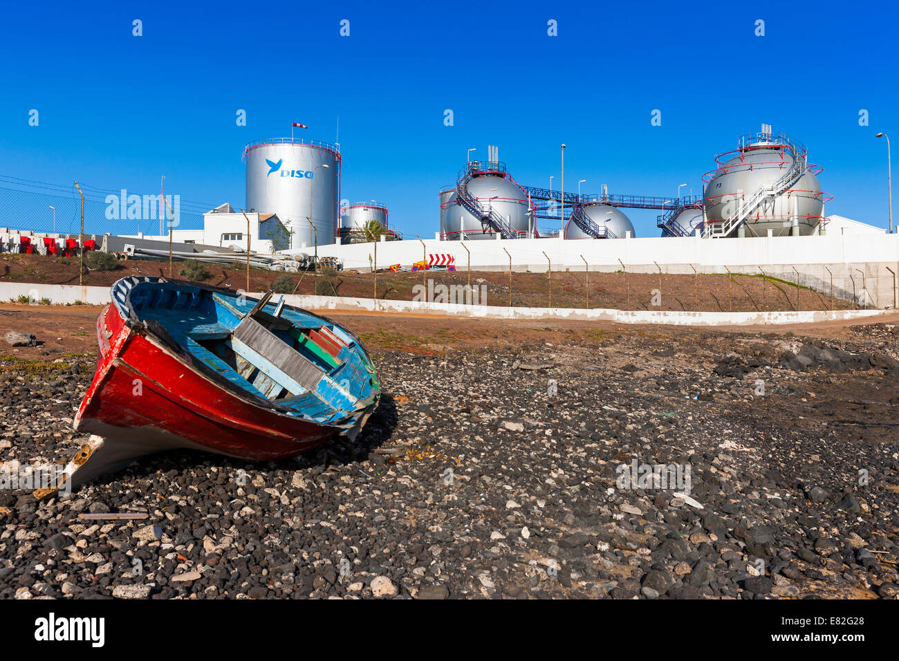 Spain, Canary Islands, Lanzarote, Arrecife, industrial plant of Disa company, wooden boat on seafront Stock Photo