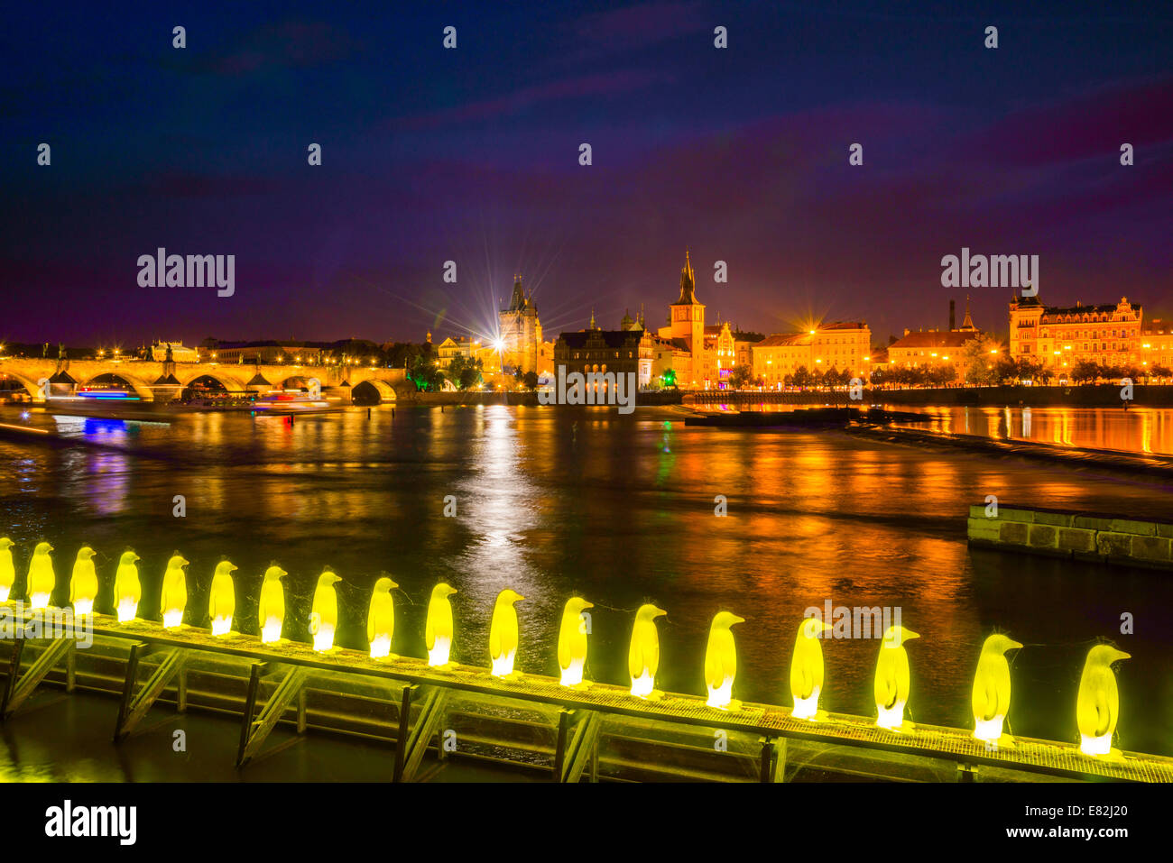 Czechia, Prague, Yellow pinguine figures, Installation of Cracking Art Group at riverside of Vltava, Old town in the background Stock Photo