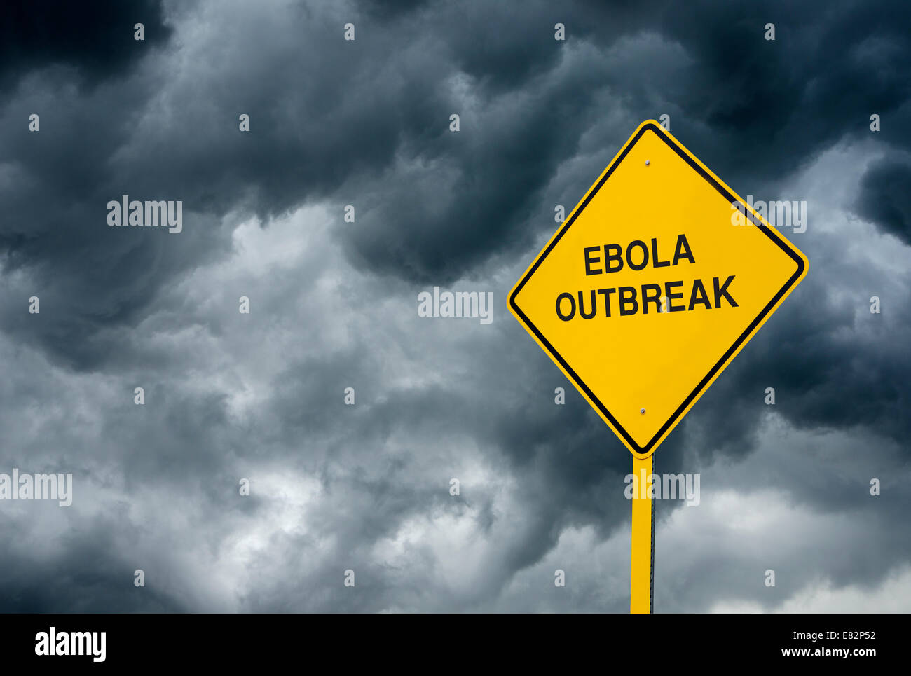 A Caution Sign in front of storm clouds warning of 'Ebola Virus Ahead'. Stock Photo