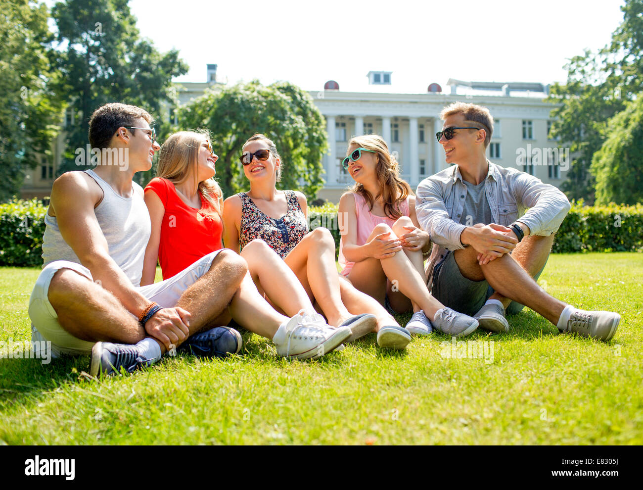 group of smiling friends outdoors sitting in park Stock Photo - Alamy