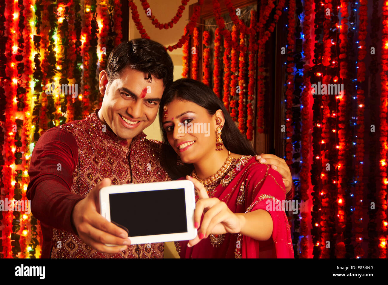 Image of Indian young couple sitting on couch while celebrating diwali /  festival or in wedding ceremony-YN660927-Picxy