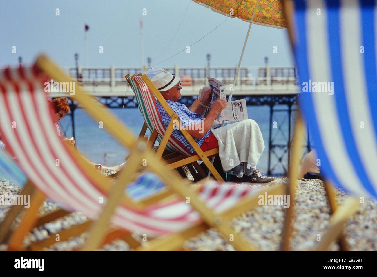 Mature man reading a newspaper on Worthing beach. Sussex Stock Photo