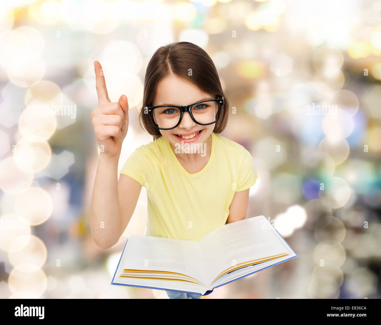 smiling little girl in eyeglasses with book Stock Photo - Alamy
