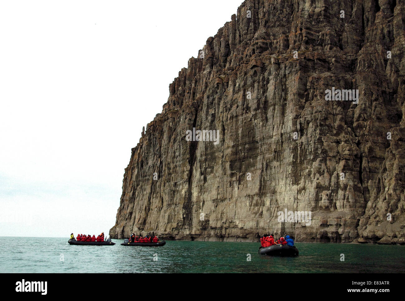 zodiaks of hopeful birdwatchers at the foot of a high cliff off the Canadian Arctic's Beechey Island Stock Photo