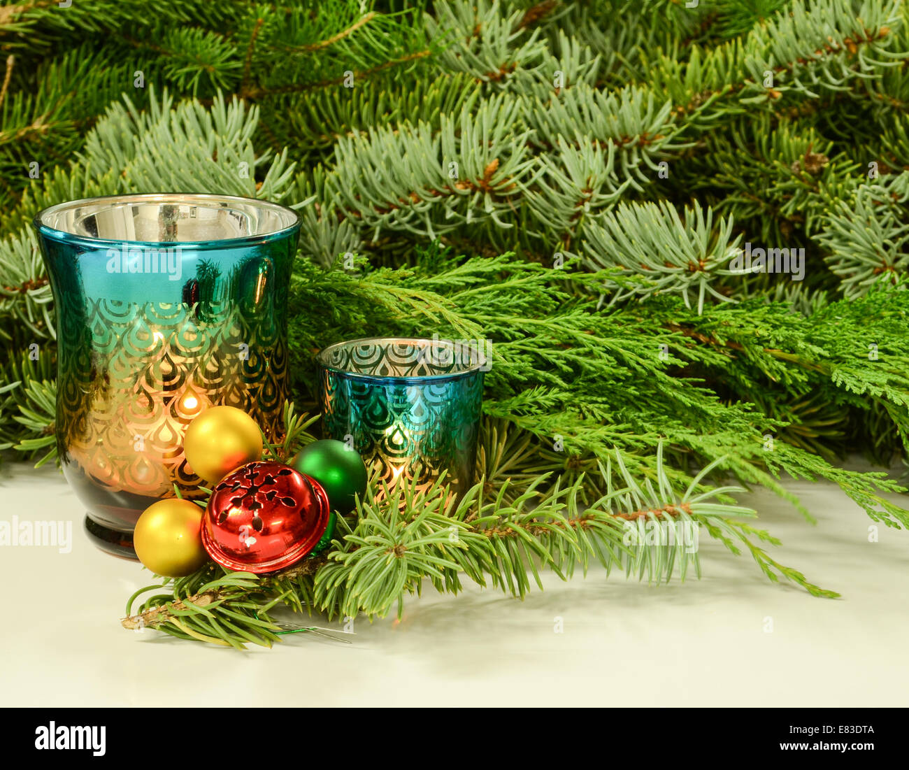 Colorful candles and Christmas ornaments in front of evergreen boughs Stock Photo