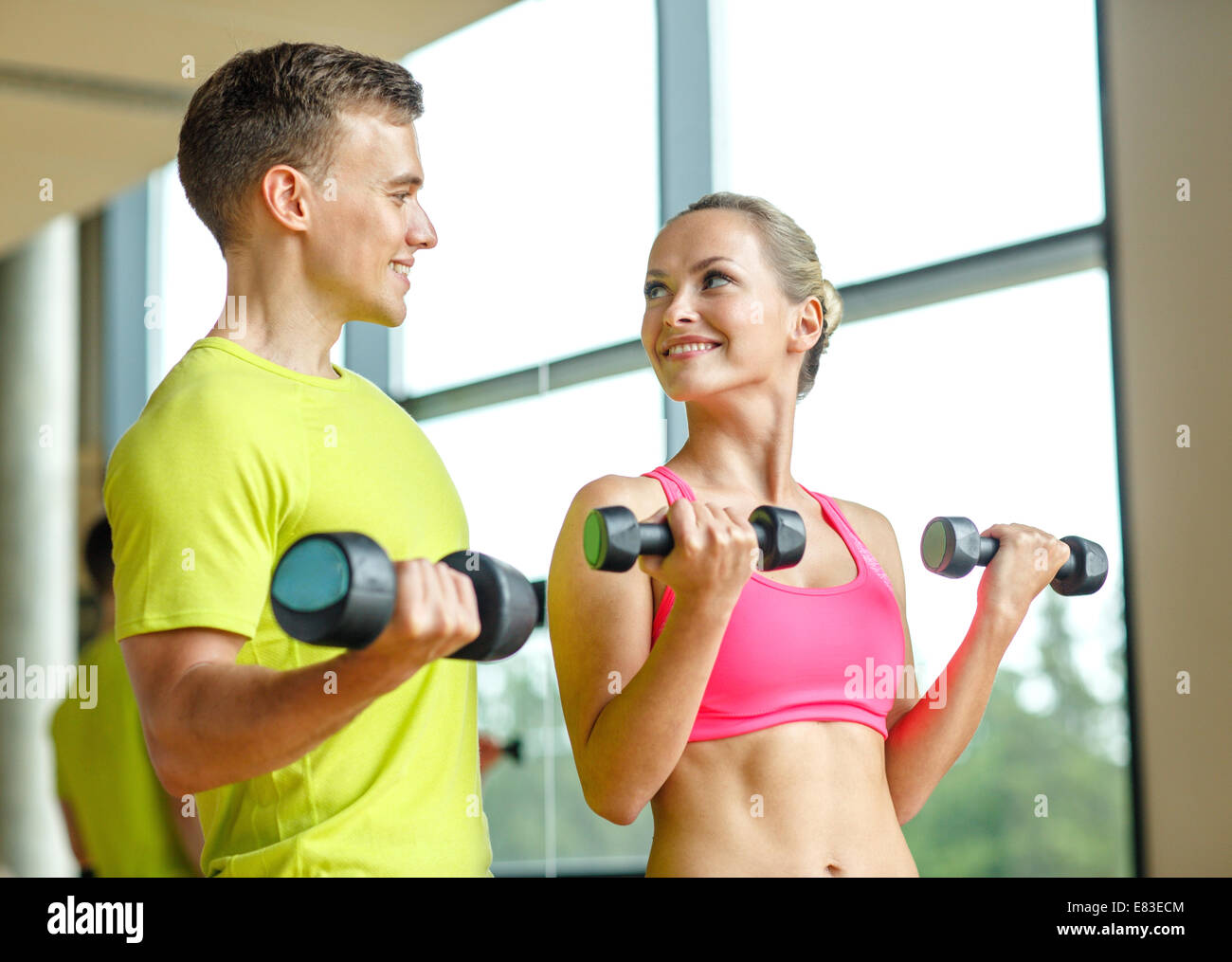 smiling man and woman with dumbbells in gym Stock Photo - Alamy