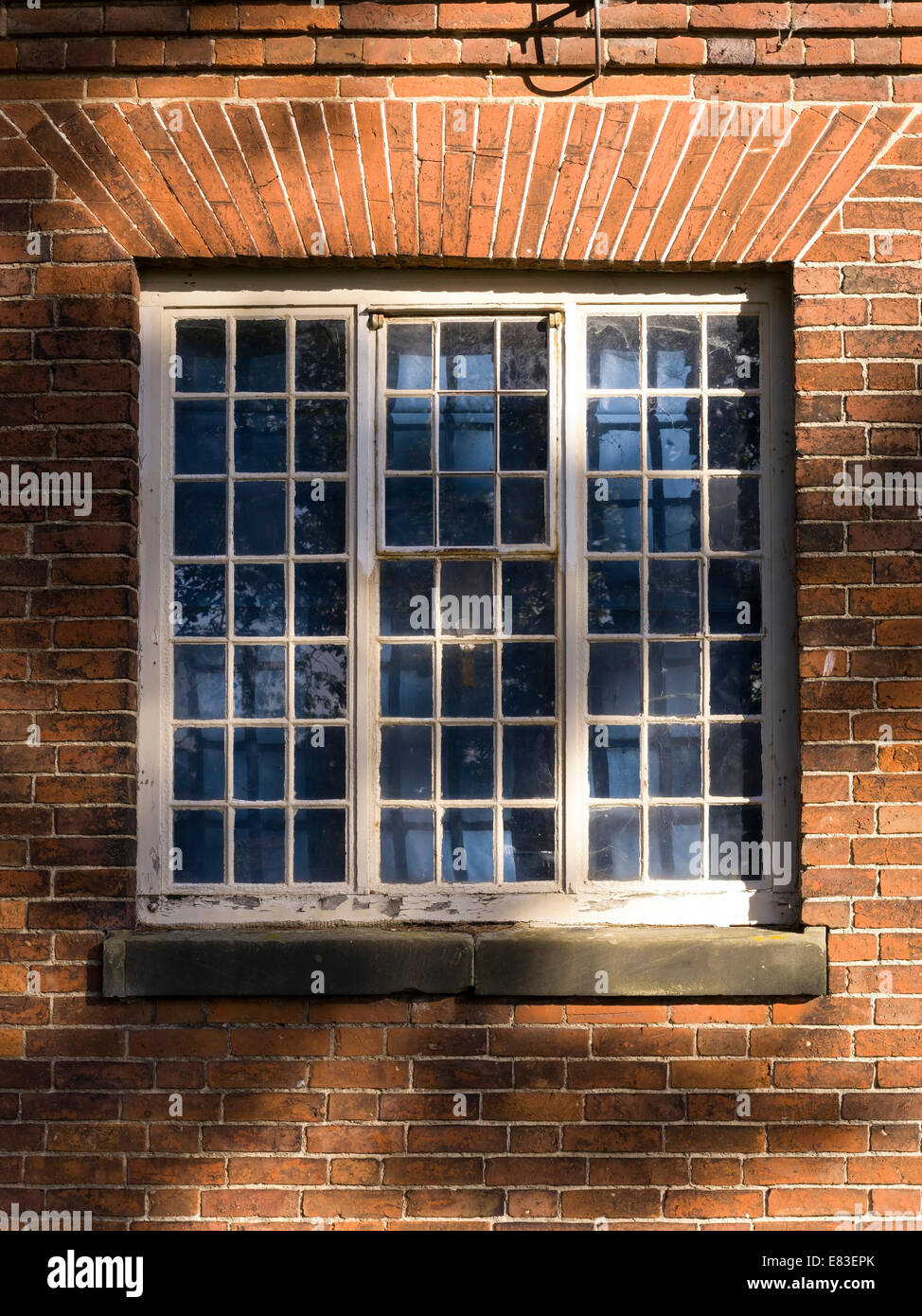 Old cross windows set into red brick wall with wedge brick lintels, Ticknall, Derbyshire, England, UK. Stock Photo